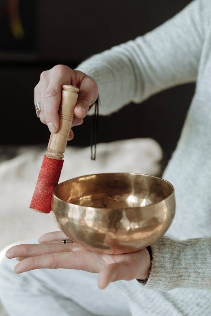 Person holding a brass singing bowl, ready for meditation with mallet.